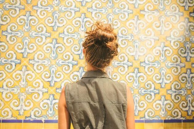 una donna di spalle che ammira un mosaico giallo e bianco
