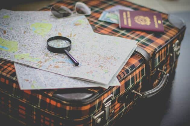solicitar la visa para Italia, lupa sobre un mapa colocado en una maleta de colores